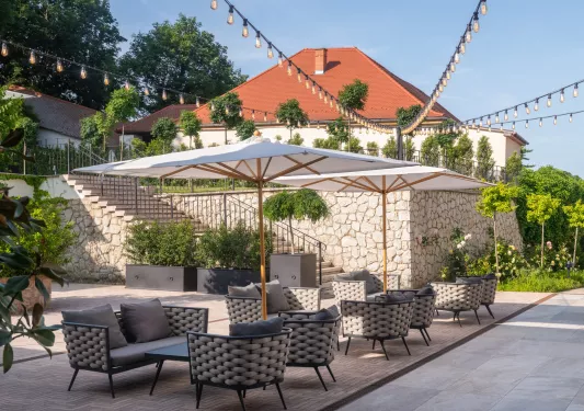 Outdoor patio with cushioned chairs, with a large stone staircase in the background