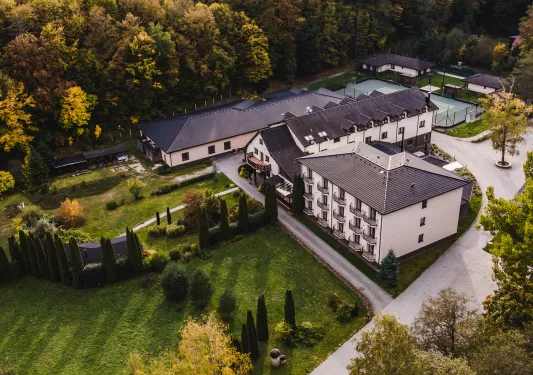 Exterior, sky view of a white hotel building with a forest in the background