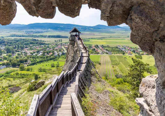 Large wooden pathway on top of a hill, overlooking a large grass valley and a small town