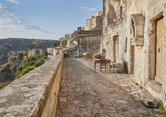 Exterior patio of rustic, stone building on a cliff, with other stone buildings in the background