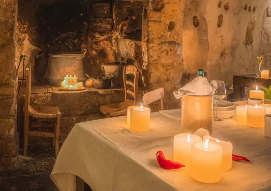 Dining table in a rustic room, with stone walls and candles along the room