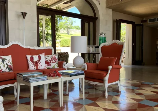 Indoor lobby with patterned floor and cushioned, red chairs