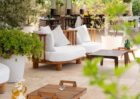 Outdoor patio with white, cushioned chairs and small wooden tables