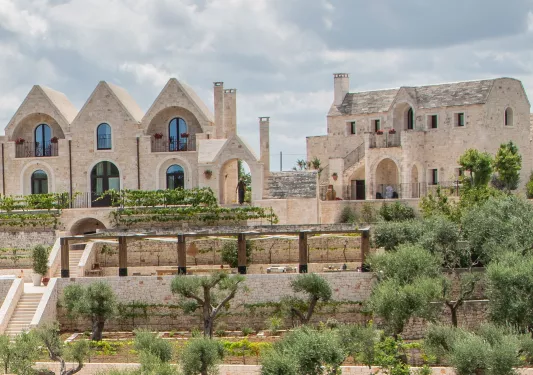Exterior view of rustic, stone buildings with large gardens in front