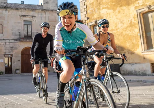 Two women and one man riding their bikes and smiling