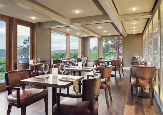 Dining hall with wooden tables and leather chairs, with wine glasses on each table