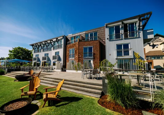 Exterior view of wood and metal hotel building, with a stone patio and large grass area
