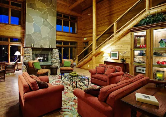 Cabin main room with cushioned, red sofas and a stone fireplace in front