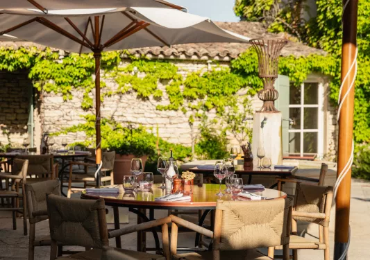 Outdoor patio with dining tables and umbrellas, with wine glasses on each table
