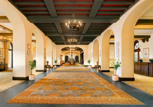 Long hotel lobby walkway with flower rugs and large archways