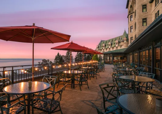 Outdoor patio and dining area in front of a large stone building with green roofing