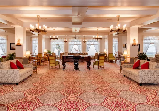 Large banquet hall with cushioned chairs and a piano in the center