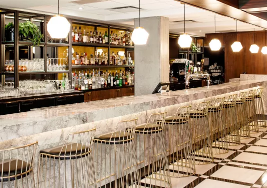 Bar and lounge with marble counters and shelving full of alcohol