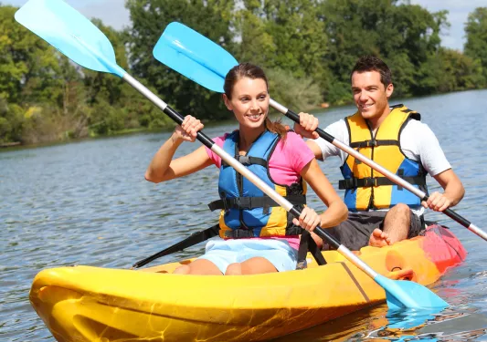Man and woman paddling in a yellow kayak