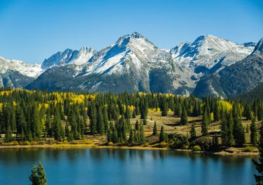 Water with trees and snow-capped mountains in the background