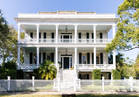 Exterior view of two-story white building with a white fence
