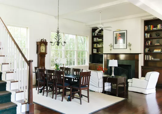 Living room with a wooden dining table over a white rug, and a fireplace to the right
