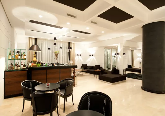 Bar and lounge with black chairs and tables, and a bar counter in the back