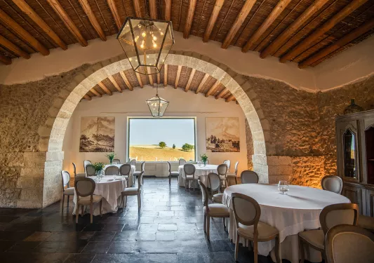 Indoor dining hall with circular tables and stone walls