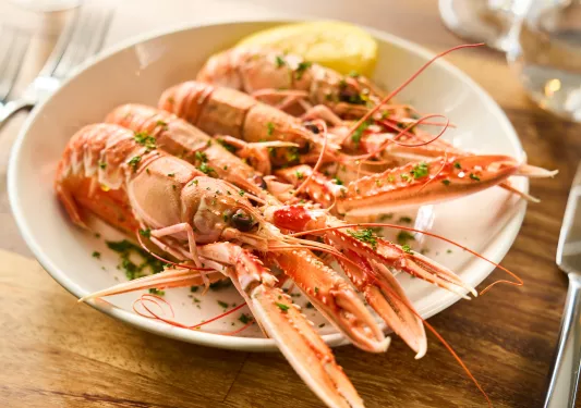 Plate of cooked prawns with a lemon wedge on the right