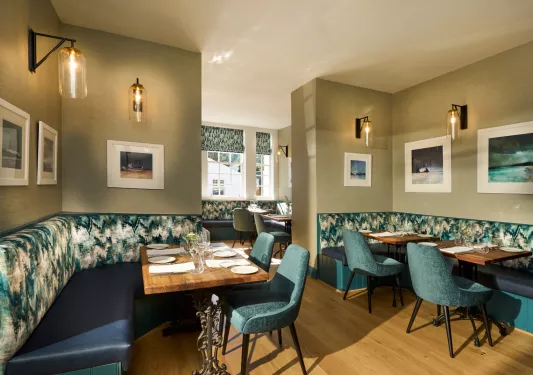 Dining hall with blue and green chairs and sofas around tables