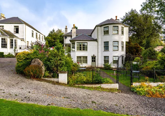 Exterior view of white and gray stone building with a small black fence in front