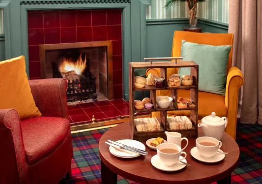 Two chairs next to a small coffee table full of pastries and cups of coffee