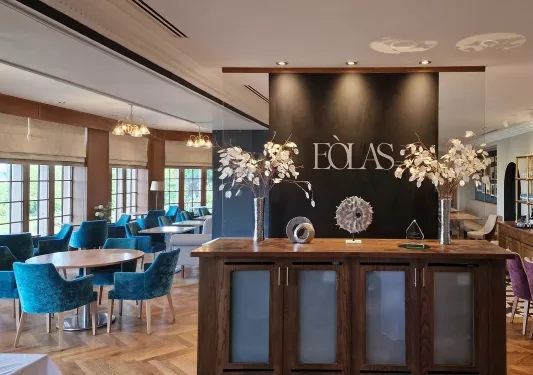Hotel lobby entrance with a counter and blue and white chairs and tables to the left
