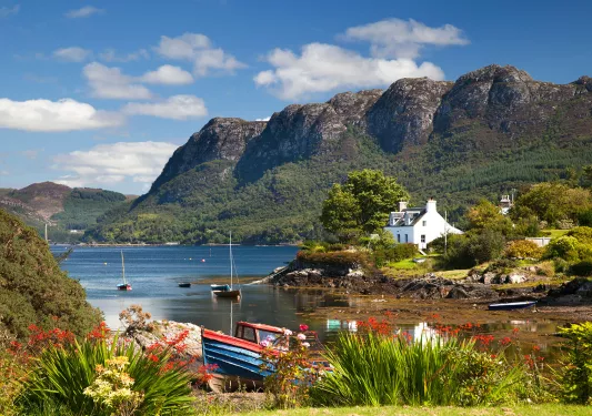 Lake with boats by the shore, and large mountains in the background