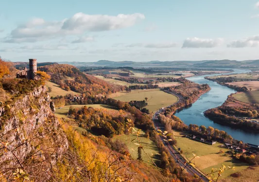 Large grass valley with orange trees and a river to the right