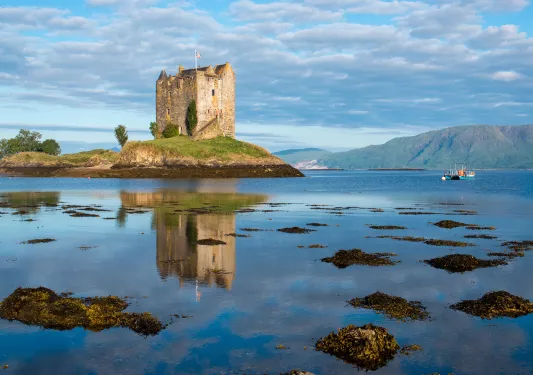 Rustic building in the middle of a lake, with a small boat to the right