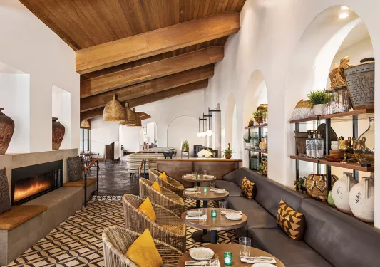 Indoor dining area with leather sofas and woven chairs, surrounding circular dining tables