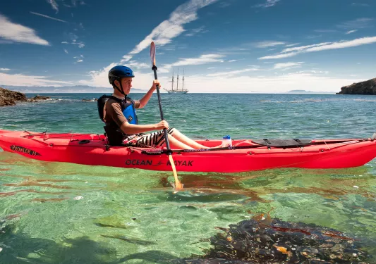 Man paddling on a red kayak in the ocean