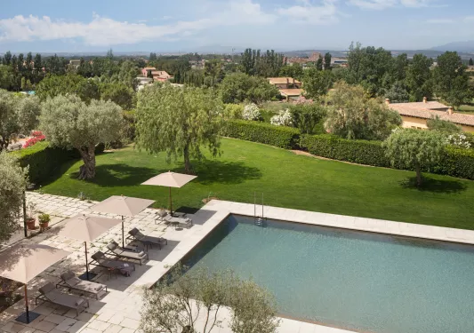Outdoor pool surrounded by reclining chairs and a large grass area