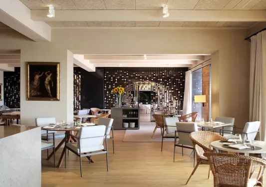 Hotel restaurant dining hall with woven chairs and square and circular tables