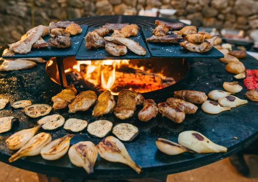 Large grill with roasted vegetables and slices of meat