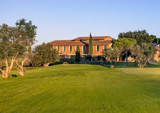 Large grass lawn leading to an orange, two-story building