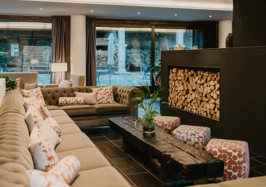 Hotel lobby with cushioned sofas in front of a large, black fireplace