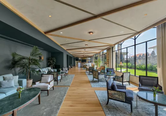 Long hallway with cushioned chairs and large windows to the right