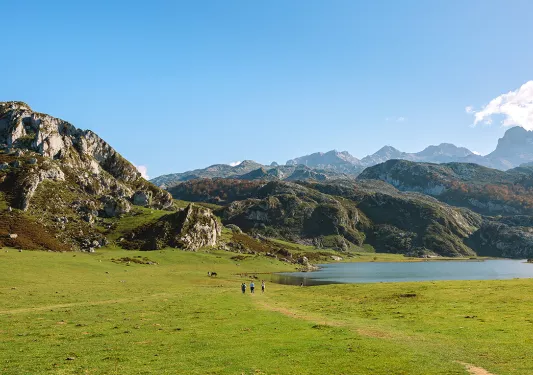 Group of people walking in a grassy valley with large cliffs in the distance