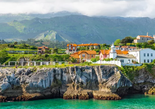 Row of houses by a cliff with the ocean in front