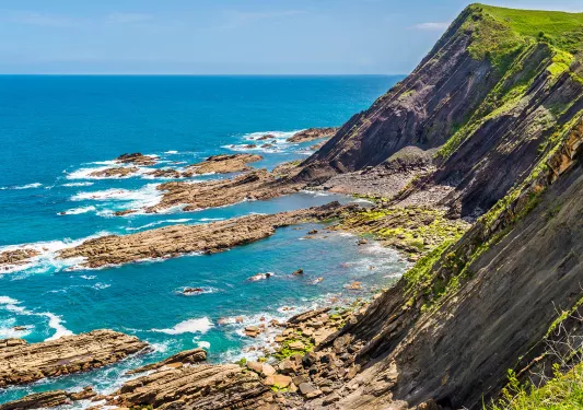 Large cliff with rocks peeking from the ocean below