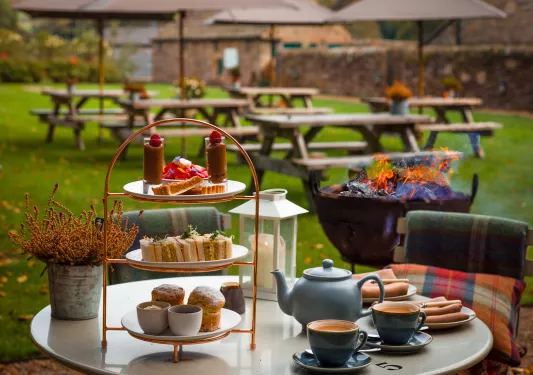 Table outdoor with tea and pastries, with benches in the background