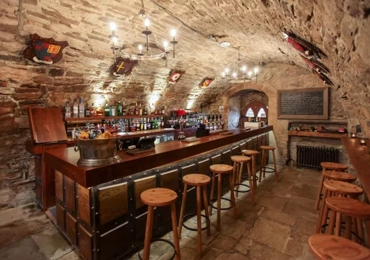 Bar and lounge in a cavern, with stone walls and alcohol lined up along the wall