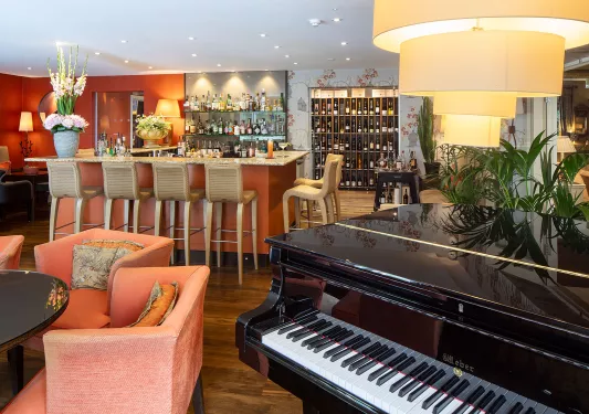 Bar and lounge with an alcohol rack in the back and a piano in front