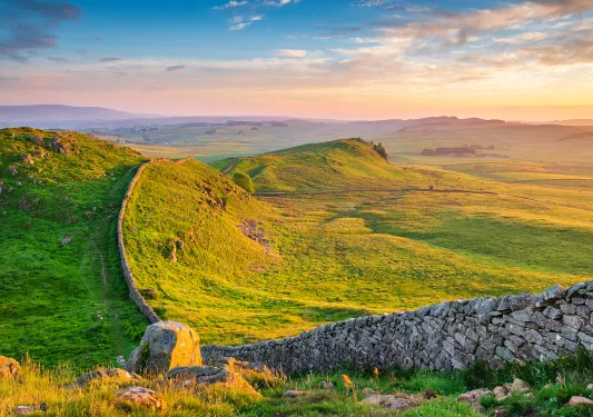 Large stone wall across a large, grassy hill