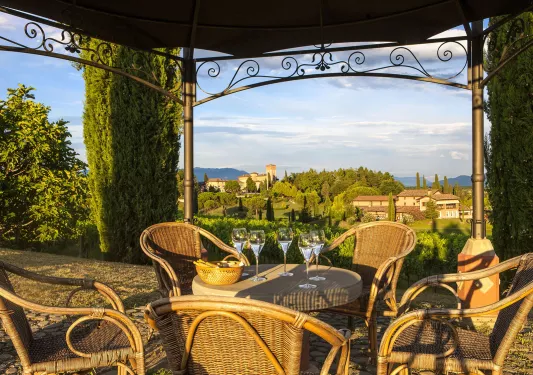 Outdoor patio with woven chairs and tables, looking out to a valley
