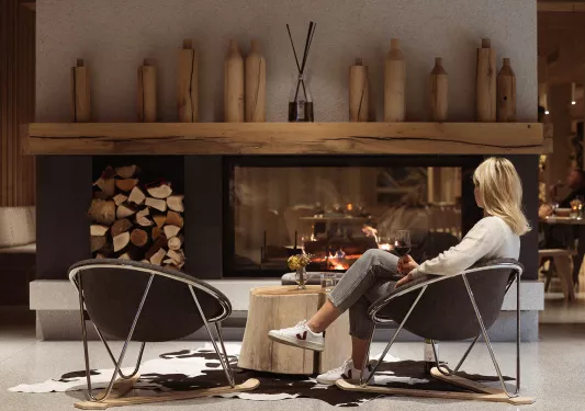 Woman sitting in front of a large fireplace with wooden sculptures above