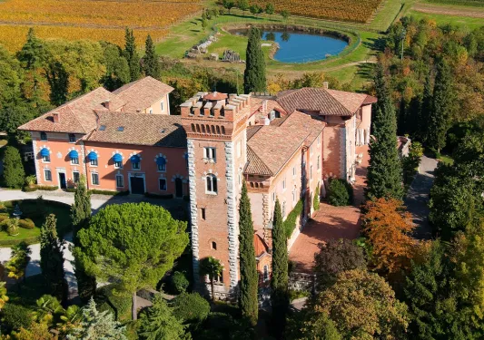 Orange and white stone building with crop valleys and ponds in the background