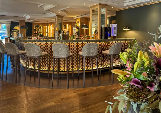 Bar and lounge with an illuminated bar and beige stools in front